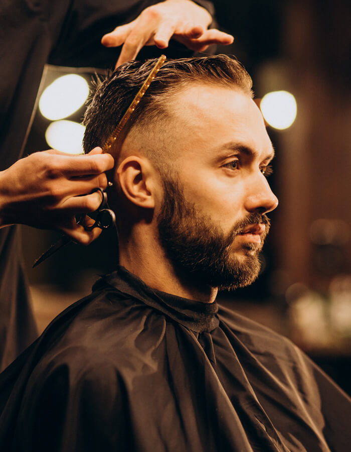 Barbier stylt modernen Fade-Haarschnitt bei einem Kunden im Friseursalon in Gießen.